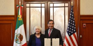 Yellen and Ramírez hold a document while standing next to Mexican and U.S. flags in a conference room.