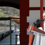 AMLO speaks at a podium alongside a train at an Interoceanic Train station