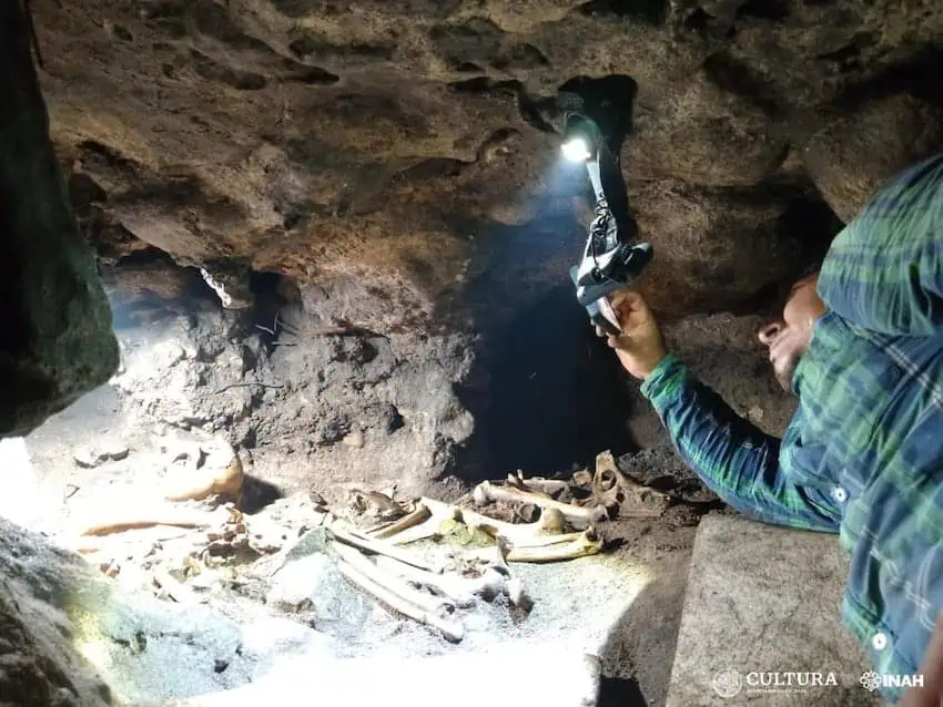A person examines human remains in a Tulum cave