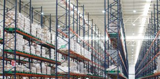 A huge warehouse with half-filled shelves and several workers in the foreground