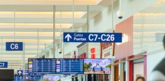 Airport gate signs hang above a crowded hallway