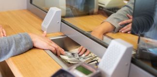 Hands push dollars under a bank sill