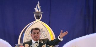 Naasón Joaquín García preaches behind a podium filled with flowers