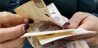 Hands flip through a stack of 500-peso bills