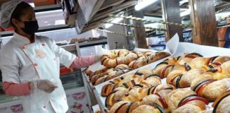 A baker displays trays full of ring-shaped king cakes decorated with strips of jewel-colored sweets, for Kings' Day in Mexico.