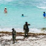 Soldiers patrol a sargassum-covered beach in Quintana Roo