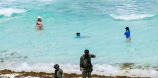 Soldiers patrol a sargassum-covered beach in Quintana Roo