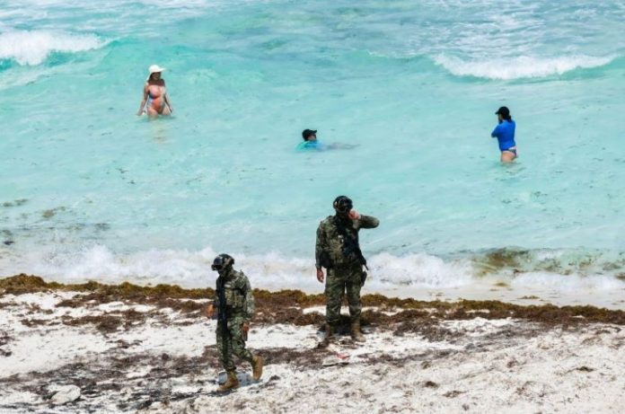 Soldiers patrol a sargassum-covered beach in Quintana Roo