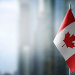 A Canadian flag in front of a blurry city background