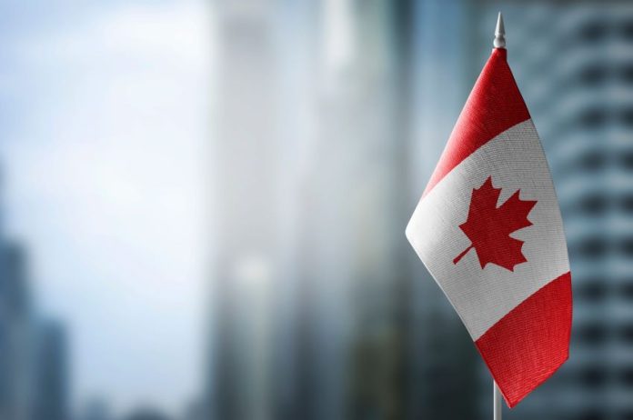 A Canadian flag in front of a blurry city background