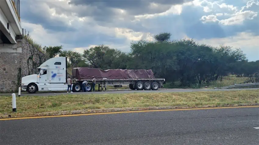 A loaded semi-trailer parked on the side of a highway.