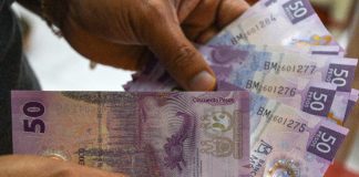 Hands holding 50 peso notes