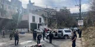 Police stand guard around the scene of a crash, with a damaged car and motorcycle