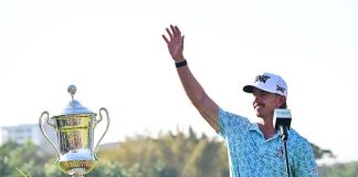 Jake Knapp waves at the crowd and accepts his golf trophy