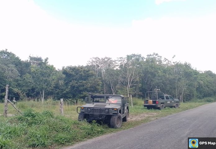 Two armored military vehicles by the side of a rural road.
