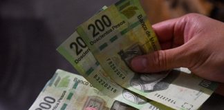 Two hands count Mexican pesos, a currency that is recovering from a recent depreciation