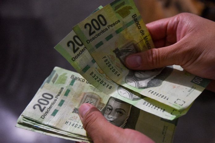 Two hands count Mexican pesos, a currency that is recovering from a recent depreciation
