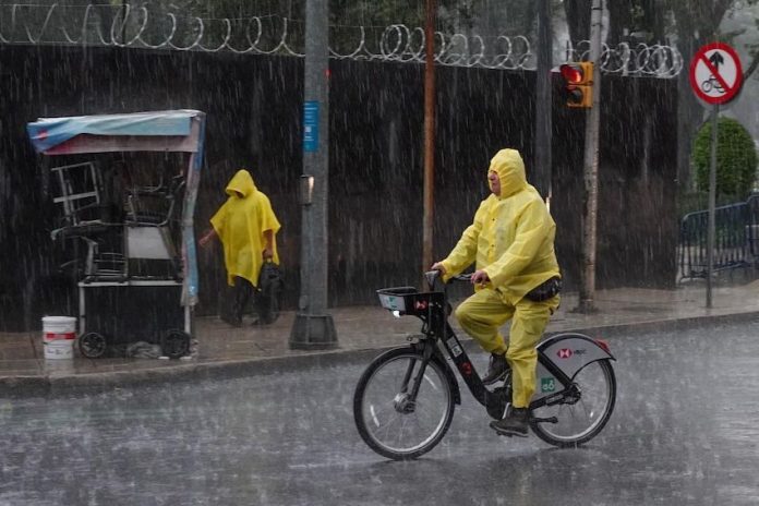 A person bicycles in the rain in Mexico City