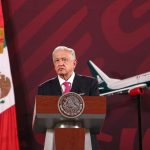 President López Obrador at a press conference with a model Mexicana airplane