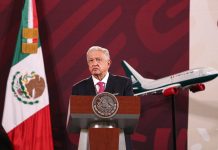 President López Obrador at a press conference with a model Mexicana airplane