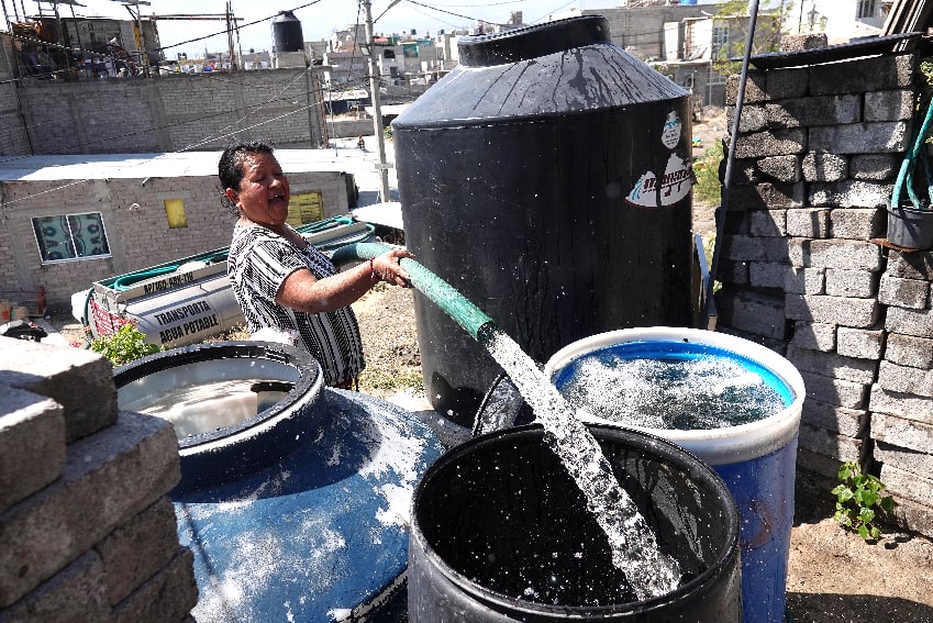 A woman fills tanks with a pipe of water