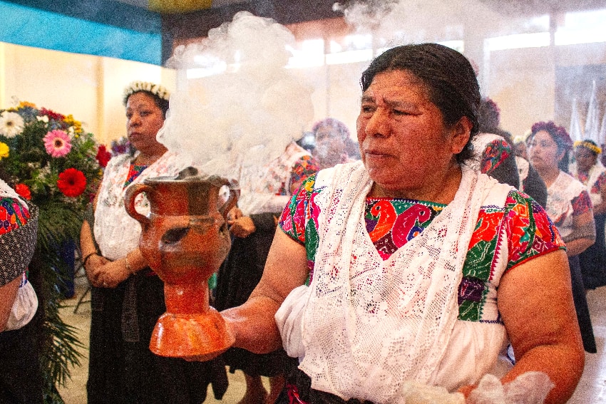 A woman holds a ceramic vessel with incense