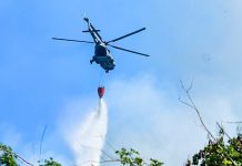 Firefighting helicopter dropping fire extinguishing chemicals over a forest