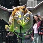Mexican woman posing for a selfie with a larger-than-life display of a bat pollinating a plant