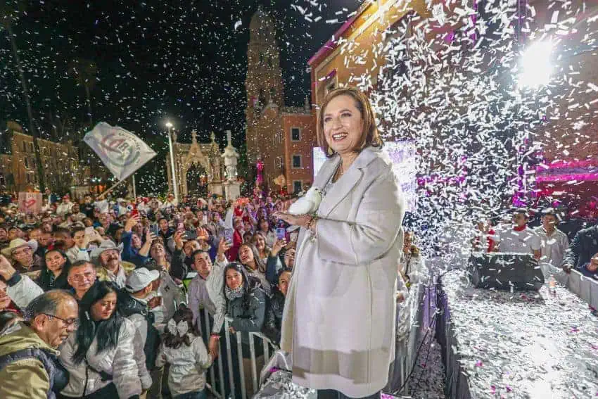 Xóchitl Gálvez stands in front of a crowd in front of a large plaza as confetti rains down
