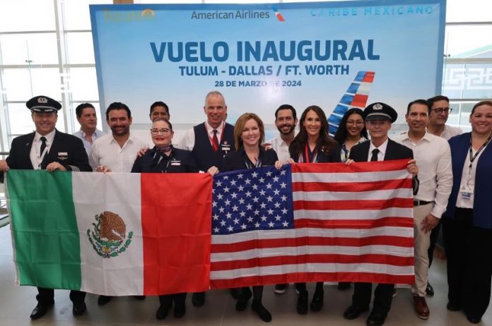 Airline and airport employees pose with a Mexican and a U.S. flag