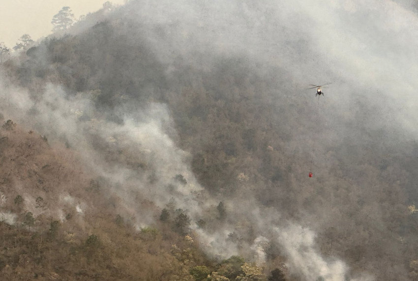 A helicopter over a smoking forest fire