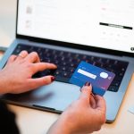 photo of a person's hands holding a credit card and entering information onto a laptop keyboard