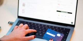 photo of a person's hands holding a credit card and entering information onto a laptop keyboard