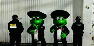 Two human-sized mariachi frog statues with police standing next to them