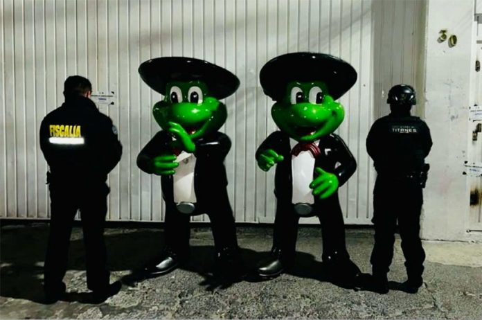 Two human-sized mariachi frog statues with police standing next to them