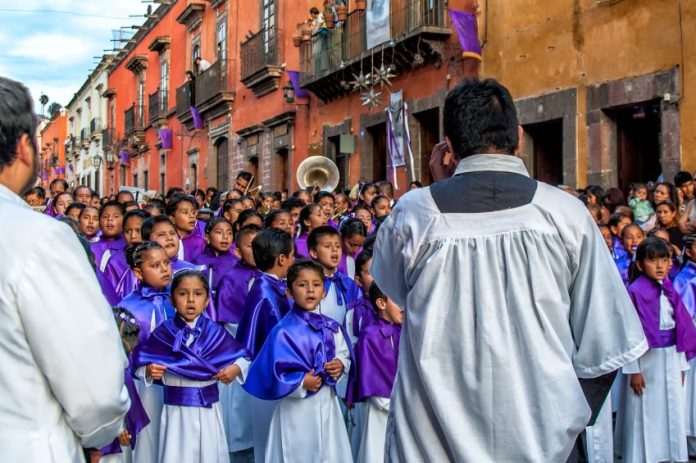 Children's choir sings in a Good Friday procession. Holy Week events attract thousands of visitors to this colonial town in Mexico.