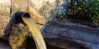 dirty water flows out of a drain in an urban area