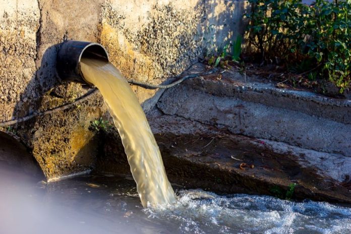 dirty water flows out of a drain in an urban area