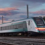 A green and silver train at sunset
