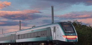 A green and silver train at sunset