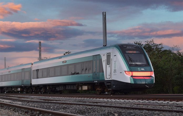 A green and silver train at sunset