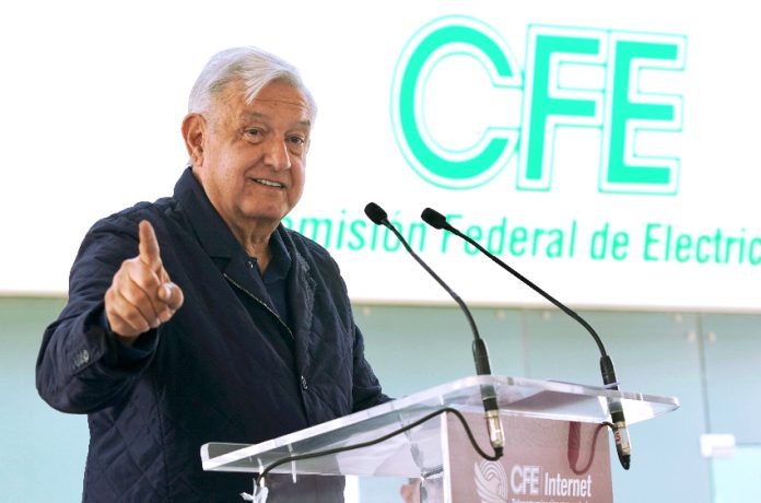 López Obrador with CFE sign behind him