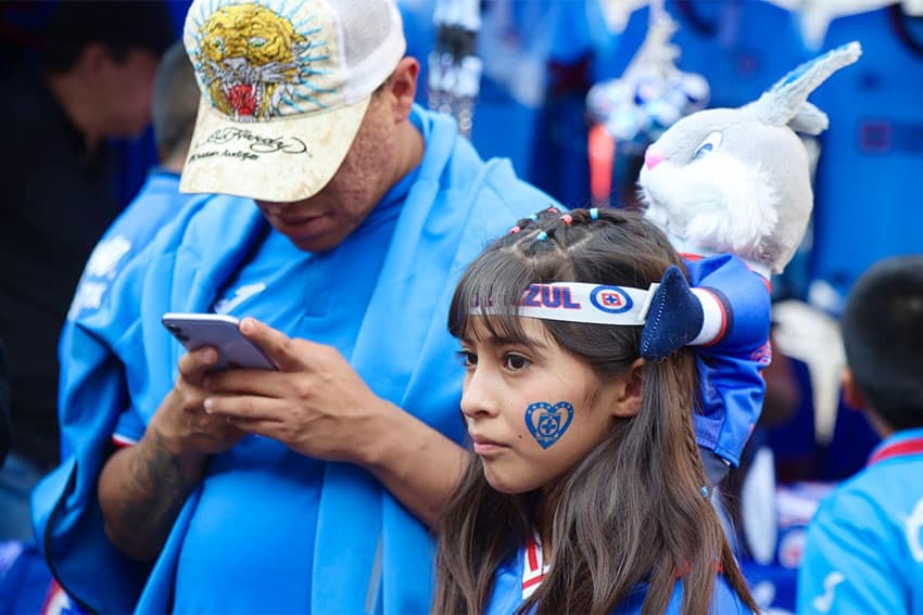 Mexico City father and daughter dressed in fan gear at a Cruz Azul soccer game