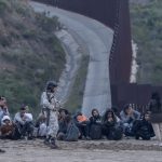Members of Mexico's National Guard stand near migrants at the border with the United States