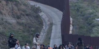 Members of Mexico's National Guard stand near migrants at the border with the United States