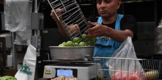 A vendor weighs vegetables at a market