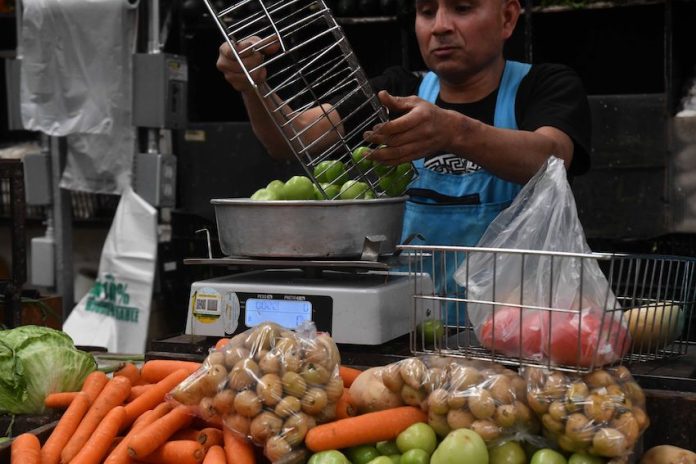 A vendor weighs vegetables at a market
