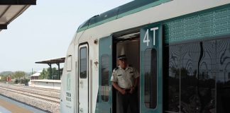 Conductor standing in doorway of Maya Train railroad car