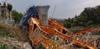 A collapsed construction crane next to a concrete bridge support