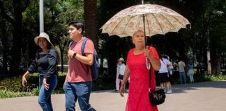 A woman shields herself from the sun with an umbrella